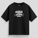 Black oversized unisex T-shirt with Malayalam text "Thrissurkaran" and mustache graphic in white print, representing Thrissur culture.