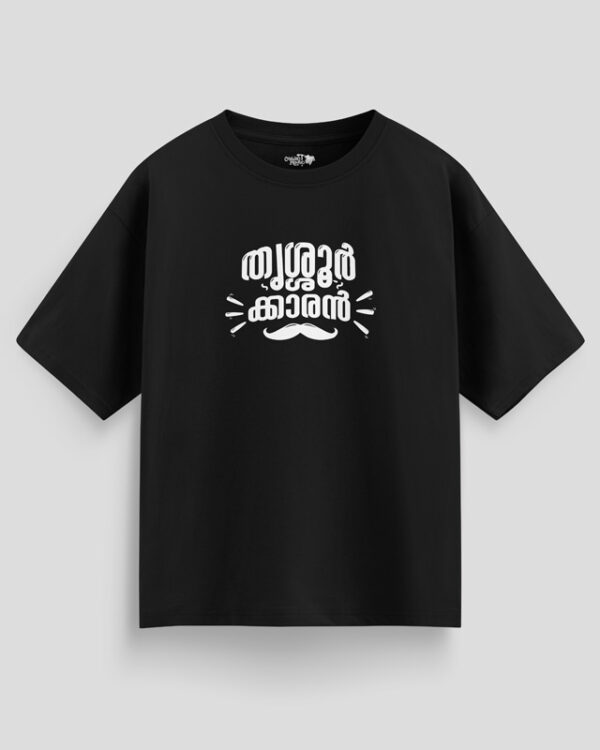 Black oversized unisex T-shirt with Malayalam text "Thrissurkaran" and mustache graphic in white print, representing Thrissur culture.