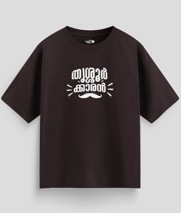 Brown oversized unisex T-shirt with Malayalam text "Thrissurkaran" and mustache graphic in white print, representing Thrissur culture.