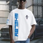 Shelby Mustang T-Shirt featuring blue GT350 car graphic on oversized white t-shirt, worn by model outdoors near Mustang car.